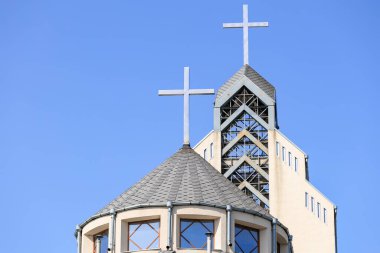 Mavi gökyüzüne karşı haçları olan modern kilise mimarisi.