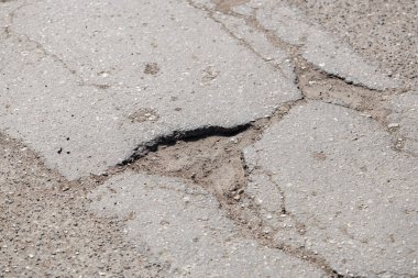 Sokak yüzeyinde asfalt çatlakları ve yol hasarı.
