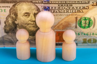 Önümüzde tahtadan figürler var. Dolar banknotları finans ve aile kavramını simgeliyor..
