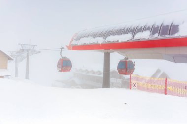 Sisli manzaralı, karlı dağ otelinde kırmızı teleferikler. 15 Aralık 2024 'te Romanya.