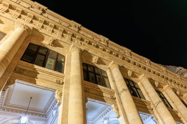 Sütunlu ve aydınlık yüzlü tarihi neo-klasik binanın gece manzarası. 8 Mart 2025 Bükreş Romanya.