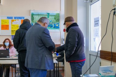 Oy verme merkezinde bilgi afişleriyle tartışan beyaz adamlar. 21 Kasım 2021 Balti, Moldova.