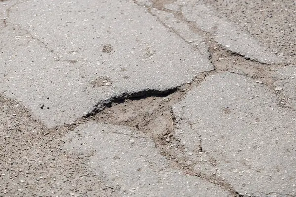 Sokak yüzeyinde asfalt çatlakları ve yol hasarı.