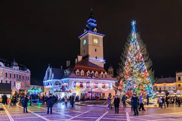 Kasaba meydanında bir Noel ağacı yanıp sönüyor. Etrafta insanlar dolanıyor. Atmosfer şenlikli ve canlı. 13 Aralık 2024 Brasov Romanya