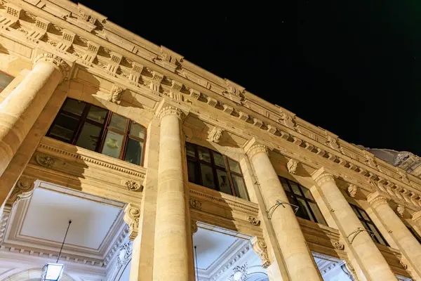 Sütunlu ve aydınlık yüzlü tarihi neo-klasik binanın gece manzarası. 8 Mart 2025 Bükreş Romanya.