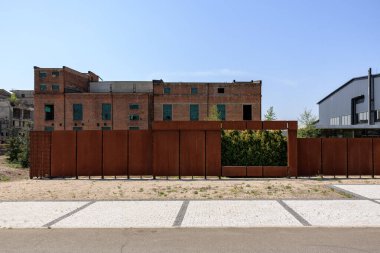 Endüstriyel kırmızı tuğla bina ve şehir merkezinde paslı metal çit..