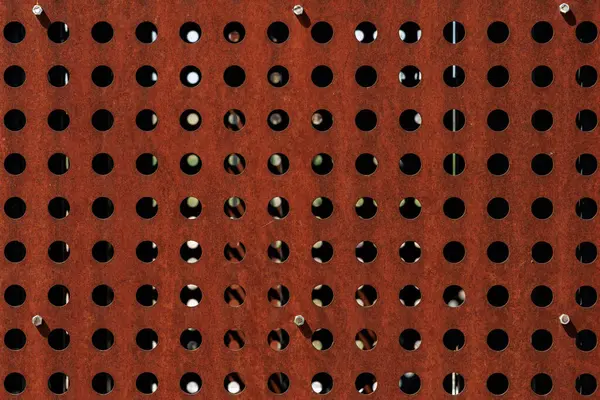 Dairesel delikli paslı metal ızgara geometrik desen oluşturuyor.