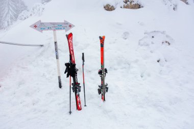 Kırmızı kayaklar ve karlı dağ manzarasında yön işaretli kutuplar. 15 Aralık 2024 'te Romanya.