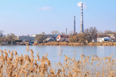 Kışın nehir kıyısında bacaları olan sanayi manzarası. 22 Şubat 2025 Balti Moldova.