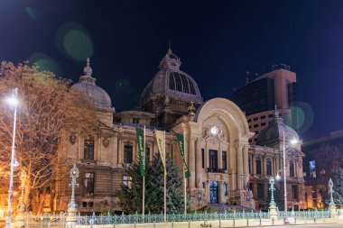 Bükreş 'teki tarihi Cec Palace' ın aydınlatılmış mimarisiyle gece görüşü. 8 Mart 2025 Bükreş Romanya.
