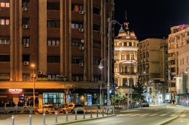 Aydınlatılmış bina ve şehir ışıklarıyla gece sokak sahnesi. 8 Mart 2025 Bükreş Romanya.