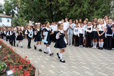 Okul üniformalı beyaz kızlar kalabalıkla açık hava seremonisinde yürüyorlar. 2 Eylül 2024 Balti Moldova.