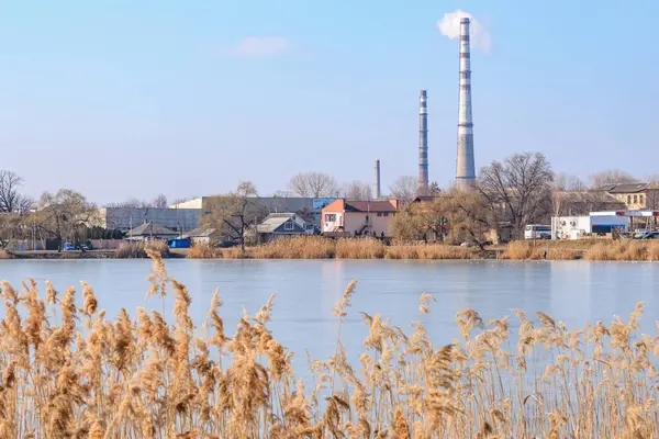 Kışın nehir kıyısında bacaları olan sanayi manzarası. 22 Şubat 2025 Balti Moldova.