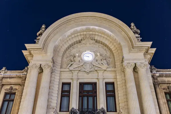 Geceleyin tarihi bina saatleriyle dekore edilmiş mimari cephe. 8 Mart 2025 Bükreş Romanya.