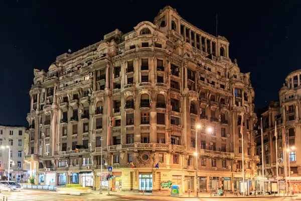 Aydınlatılmış sokak lambalarıyla tarihi Avrupa binasının görkemli gece manzarası. 8 Mart 2025 Bükreş Romanya.