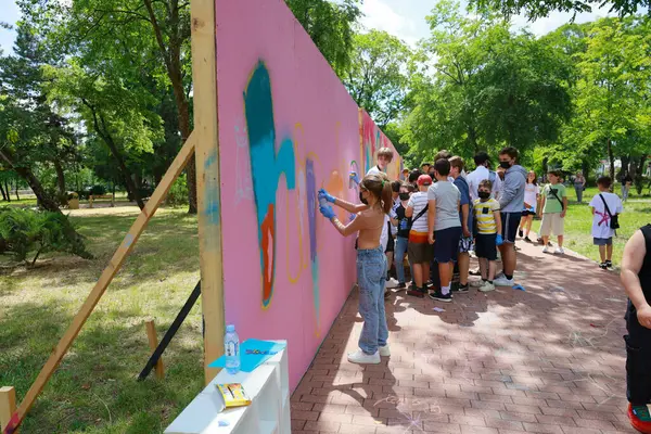Bir grup genç parktaki pembe duvarda grafiti sanatıyla uğraşıyorlar. 31 Mayıs 2024 Balti Moldova.