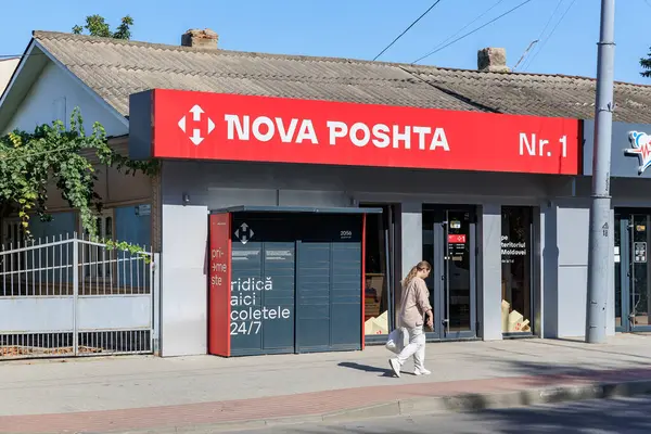Parsel kilitli Nova Posta Ofisi ve güneşli bir günde kadın yaya. 9 Eylül 2024 Balti Moldova.
