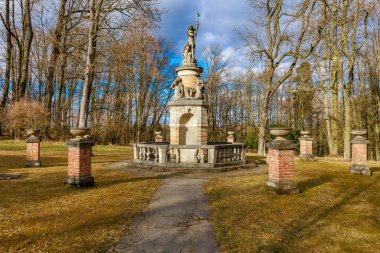 Bulutlu gökyüzünün altındaki orman parkındaki tarihi taş anıt..