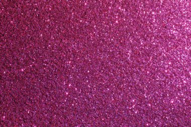 Pembe parlak bir arka plan yakın plan. Parıltı arka fonun her tarafına dağılmış, ışıl ışıl ve neşeli bir görünüm veriyor.