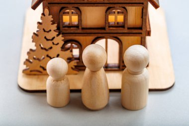 Minyatür ev modelinin önünde aileyi temsil eden tahta figürler..