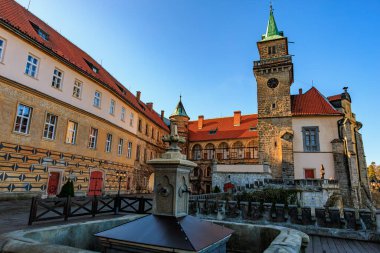 Güneşli bir günde saat kulesi ve çeşmesi olan tarihi şato..