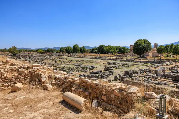 Arkasında taş bir duvar olan geniş açık bir alan. Alan boş ve gökyüzü temiz. Yunanistan 'ın antik Filippi kentinin kalıntıları