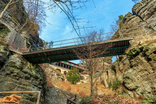 Kışın yeşillik ve açık mavi gökyüzü ile kaya oluşumunda tarihi taş köprü..