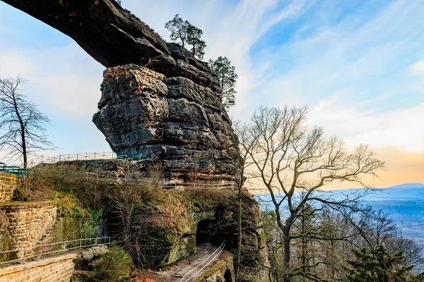 Resimli günbatımı manzarasında ağaçlar ve patikalarla görkemli doğal kaya kemeri..