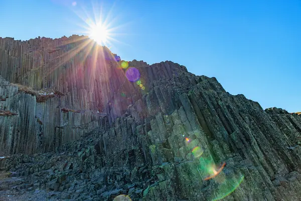 Çek Ulusal Anıtı 'ndaki Panska Skala' da açık mavi gökyüzüne karşı güneşli bazalt sütunlar.