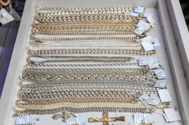 Vitrinde fiyat etiketleri olan çeşitli altın ve gümüş zincirler. 3 Kasım 2023 Balti Moldova.