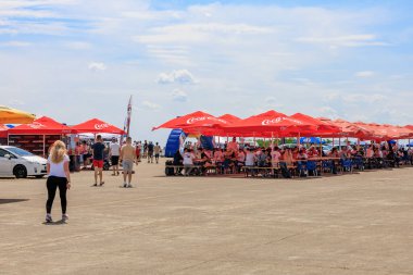Ziyaretçiler parlak kırmızı şemsiyeler altında toplanarak, canlı bir açık havada gölgeli oturma ve günlük sohbetlerin keyfini çıkarıyorlar. 2 Temmuz 2023 Liadoveni Moldova.