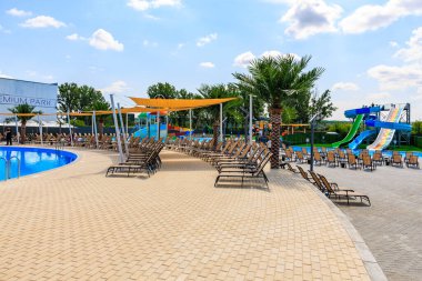 Havuzu ve kaydırağı olan bir plaj. Bir sürü şezlong ve şemsiye var. Sahne rahat ve eğlenceli. 8 Haziran 2024 Balti Moldova