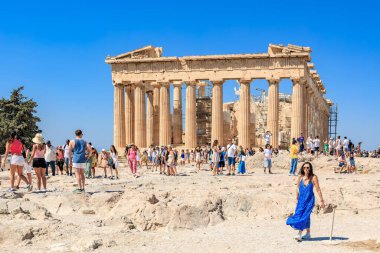 Büyük bir grup insan büyük bir binada sütunlarla yürüyorlar. İnsanlar dağıldı ve bazıları sırt çantası taşıyor. Manzara hareketli ve hareketli. 9 Ağustos 2024 Atina Yunanistan