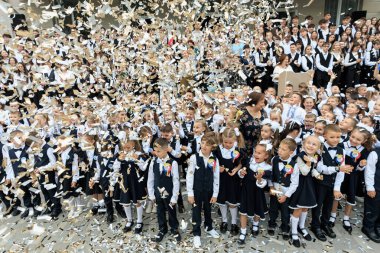 Konfeti ve üniformalı küçük çocuklarla neşeli bir okul kutlaması. 2 Eylül 2024 Balti Moldova.