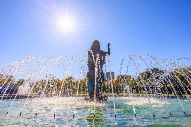 Bir kadın heykeli fıskiyenin içinden su fışkırıyor. Çeşme ağaçlarla çevrili ve gökyüzü açık ve mavi. 27 Ekim 2024 Chisinau Moldova