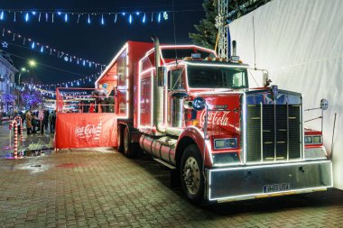 Coca-Cola kamyonu ve tatil ışıklarıyla şenlikli bir gece sahnesi. 27 Aralık 2024 Balti Moldova.