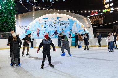 Çeşitli gruplar gece buz pateni pistinde festival ışıkları altında eğleniyorlar. 27 Aralık 2024 Balti Moldova.