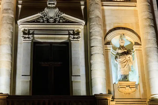 Geceleyin klasik heykelle tarihi bina cephesini aydınlatmış. 8 Mart 2025 Bükreş Romanya.