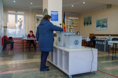 Seçim görevlileri görev başındayken oy kullanan olgun, beyaz bir kadın. 21 Kasım 2021 Balti, Moldova.