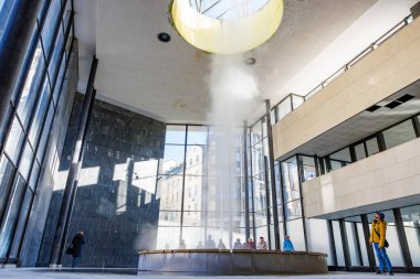 Modern binada kaynayan fıskiye ve gözlemcilerle birlikte mimari iç mimari. 18 Mart 2025, Karlovy Vary, Çek Cumhuriyeti.