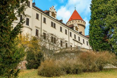 Yeşilliklerle çevrili kırmızı çatılı ortaçağ Avrupa kalesi. 17 Mart 2025, Konopiste Şatosu, Çek Cumhuriyeti.