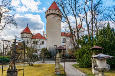 Mavi gökyüzünün altında yapraksız ağaçlarla çevrili tarihi Avrupa kalesi. 17 Mart 2025, Konopiste Şatosu, Çek Cumhuriyeti.