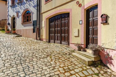 Renkli Avrupa mimarisi ve ahşap kapıları olan büyüleyici bir kaldırım taşı caddesi. 18 Mart 2025, Madalyon, Çek Cumhuriyeti.