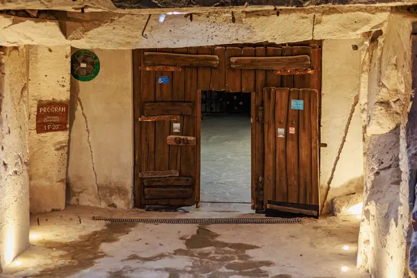 Taştan duvarda ahşap bir kapı ve antik binada sıcak ışıklandırma. 6 Nisan 2025 Branesti, Moldova.