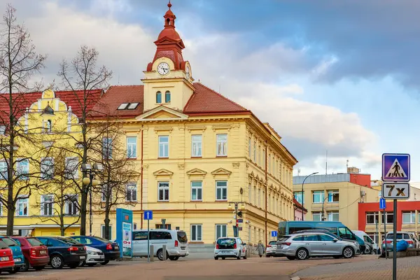 Sokak ve arabalarla şehir merkezinde saat kulesi olan tarihi sarı bina. 17 Mart 2025, Benesov, Çek Cumhuriyeti.