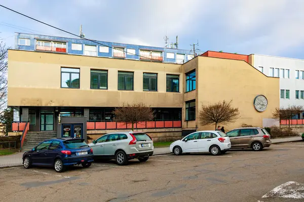 Bulutlu bir günde banliyö ofis binasında saat ve park etmiş arabalar. 17 Mart 2025, Benesov, Çek Cumhuriyeti.