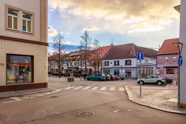 Gün batımında, köşedeki dükkanlar ve arabalarla sakin bir Avrupa kasabası caddesi. 17 Mart 2025, Benesov, Çek Cumhuriyeti.
