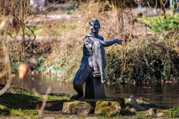 Park ortamında oturan kadın figürünün bronz heykeli. 19 Mart 2025, Karlovy Vary, Çek Cumhuriyeti.