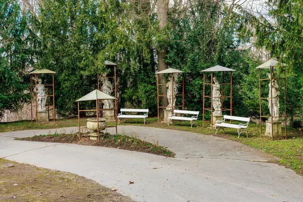 Parkta heykeller ve banklar olan sakin bir bahçe. 17 Mart 2025, Konopiste Şatosu, Çek Cumhuriyeti.