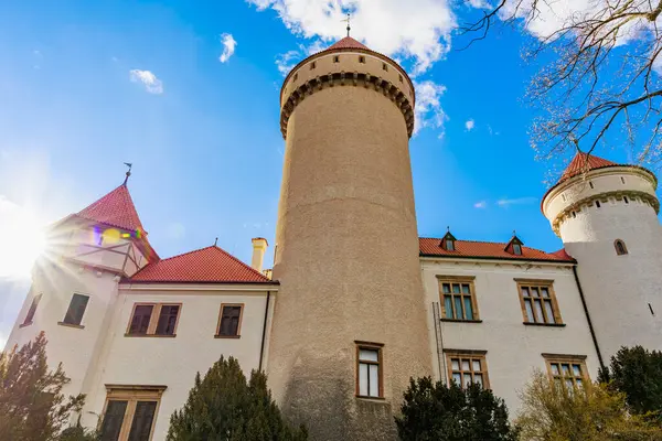 Kırmızı çatıları ve mavi gökyüzünün altında kuleleri olan tarihi bir şato. 17 Mart 2025, Konopiste Şatosu, Çek Cumhuriyeti.
